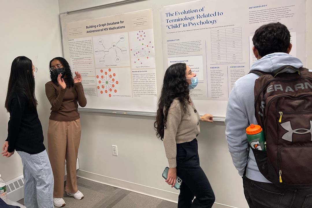 Data Science undergraduate students looking at research posters hung up on a whiteboard