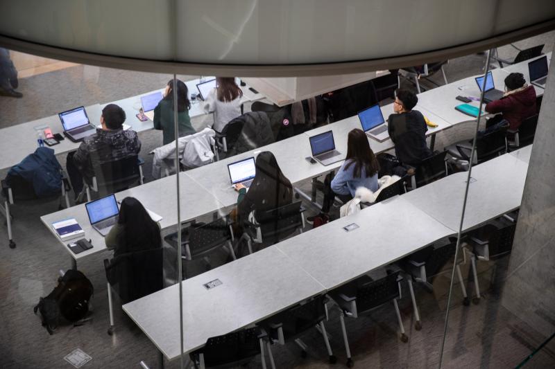 Three rows of students at large classroom tables
